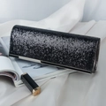 Elegant black sequin clutch evening bag with silver trim on white silk backdrop - Black + Gunmetal