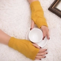 Détail de mitaines en maille jaune gingembre tenant une tasse blanche sur tapis doux - Taille unique / Jaune