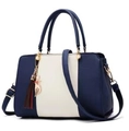 Detail van de blauw-beige leren tas met lychee-korreltextuur en kattenkwast-hanger - Koningsblauw