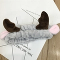 Detailopname van een grijze pluche hoofdband met bruin gewei op een houten achtergrond - Grijs