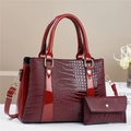 Detail view of burgundy faux crocodile tote bag with matching coin purse and gold hardware - Red