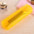 Translucent yellow portable toothbrush and makeup brush storage case on wooden surface - Orange