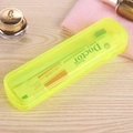 Portable neon green travel toothbrush and toothpaste storage set on a wooden desk - Yellow