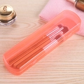 Translucent orange portable organizer box with makeup brushes on a wooden surface - Pink