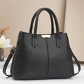 Close-up of black lychee grain leather handbag with elegant gold metal hardware and texture - Black