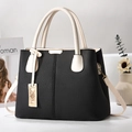 Close-up of black and cream contrast handbag with pebbled leather texture and gold hardware - Black and White Patchwork