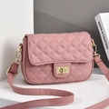 Pink quilted crossbody bag with golden twist lock and leather strap on display stand - Pink