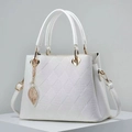 Close-up of white lychee leather texture with quilted stitching and golden leaf charm - White