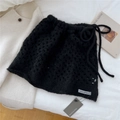 Détail de la jupe en tricot noir montrant le tissage au crochet et le logo Ocio Guantes - Noir
