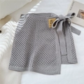 Detail eines grauen Strickwickelrockes mit seitlicher Schleife und Lochstrickmuster - Einheitsgröße / Grau