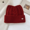 Detail of red chunky cable knit wool hat with cat ears and small metal logo plate - 24*20cm / Red
