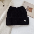 Détail d'un bonnet en maille torsadée noire avec revers et étiquette métallique - Noir