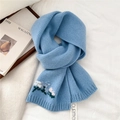 Gros plan sur une écharpe en laine tricotée bleu clair avec broderies florales blanches et roses - Bleu