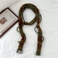 Detail of striped knit scarf in olive green and brown colors on white bedding - Green and Brown Stripes