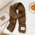 Nahaufnahme eines braunen Strickschals mit klarem Maschenbild und weißem Webetikett-Detail - 11*165cm / Braun Mit Taschen