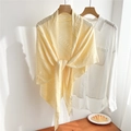 Detail of light yellow openwork knit shawl tied over a white shirt on wooden hanger - Beige