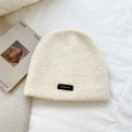 Detalle de gorro de punto crema con textura de mohair y parche de logotipo negro - 24*23cm / crema