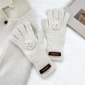 Detail of cream knit gloves featuring handmade floral crochet and vintage woven wrist label - Gloves / Beige
