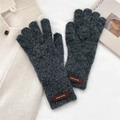 Macro detail of dark grey thick knit gloves with a brown leather label on the wrist - Gloves / Dark Gray