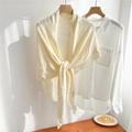 Detail view of cream beige knitted shawl featuring intricate hollow lace and tie-up front - Cream