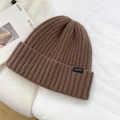 Close-up of thick ribbed knit texture and brand label on a brown wool beanie - One Size / Dark Coffee