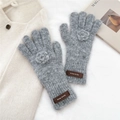 Detail shot of grey knitted mittens with crochet flower and leather brand patch - Gloves / Light Gray
