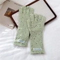 Detalle de guantes de punto mezcla verde claro con etiqueta tejida sobre tela blanca - Verde Jaspeado