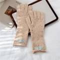 Detalle de guantes de punto beige con motas rojas y etiqueta sobre bandeja blanca - Albaricoque Moteado