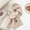 Close-up of beige wool blend ribbed knit scarf texture with a minimal black woven label - Beige