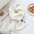 Close-up of white knit wool scarf with textured weave and premium brand woven labels - Cream