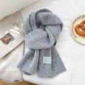 Détail de l'écharpe en maille tweed grise avec étiquette sur fond de lin blanc - Gris Moucheté