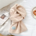 Détail de l'écharpe en tricot montrant la laine beige chinée et l'étiquette décorative - Abricot Moucheté