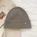 Close-up of gray ribbed knit beanie texture and leather logo patch on cuffed brim - Mocha