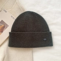 Close-up of dark grey-green ribbed knit beanie featuring a small logo and soft texture - Smoke