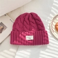 Detail of fuchsia wool knit beanie with thick cable texture and 100% wool label - 25*22cm / Rose Red