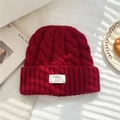 Detailed macro view of dark red 100% wool knit beanie with chunky cable texture and label - 25*22cm / Red