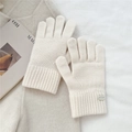 Detailed close-up of cream knit gloves with ribbed cuffs and round metal logo plate - One Size / Creamy White