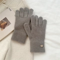 Close-up of grey knit gloves with elastic ribbed cuffs and decorative brand label - One Size / Mocha