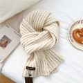 Détail d'une écharpe en maille crème avec texture côtelée et étiquette de marque - Blanc Cassé