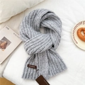 Detail of grey chunky knit scarf texture with a brown leather logo tag on white bedding - Light Gray