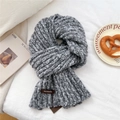 Macro shot of dark grey chunky knit scarf texture with a brown leather logo tag - Black and White