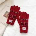 Close-up of red knit gloves with snowflake patterns and ribbed cuffs on white fabric - One Size / Red