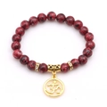 Red jasper beaded bracelet with gold Om charm and rhinestone spacers on white background - Red Spotted Stone (Om Symbol)
