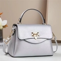 Detailed macro of silver pebble leather texture and gold shield buckle on the crossbody bag - Silver