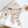 Close-up of cream knit hooded scarf featuring premium ribbed texture and brand wash label - Cream