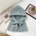 Gros plan détaillé d'une cagoule en tricot bleu clair avec nœud et bouton blanc - Bleu Clair Chiné Avec Bouton