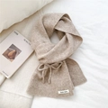 Detail view of oatmeal knit scarf with a bow design and a woven brand label - Beige Coffee Bow