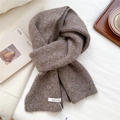 Macro detail of dark brown wool knit scarf with brand label on a cozy background - Coffee