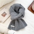 Detailed close-up of thick gray wool knit scarf texture with a white branded label - Medium Grey