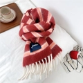Detail of red and peach striped wool scarf with white tassels in a cozy winter setting - Large Label Style / Red (Striped)
